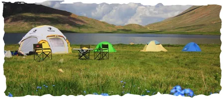 Deep blue waters of Sheosar Lake surrounded by sweeping green plains in Deosai National Park Skardu