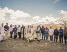 Group of senior travelers and corporate guests at Babusar Top with snow-capped hills in Naran Kaghan