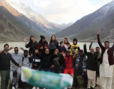 Family group tour celebrating with raised hands at scenic Lake Saif-ul-Malook in Naran Valley