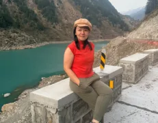 Foreign female tourist sitting by the roadside with scenic river views in Naran Kaghan Valley