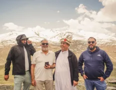 Four male travelers including an international guest smiling at Babusar Top in Naran Kaghan Valley