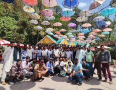 Group of male tourists posing under colorful hanging umbrellas at the Patriata chairlift market in New Murree with Pakistan Tour & Travel