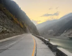 Paved mountain road winding through Naran Kaghan Valley with River Kunhar on the right and mountains on both sides