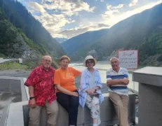 Two senior couples sitting by the roadside with a river and mountains in the background in Naran Kaghan Valley