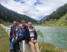 Two senior foreign couples posing by the edge of a scenic lake surrounded by mountains in Naran Kaghan Valley