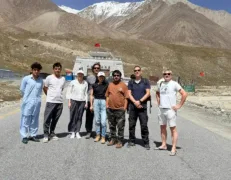 Foreign Tourists and Tour Guide at Khunjerab Pass Border Gate Foreign couples and local tour guide posing on the road in front of the Pak-China border gate at Khunjerab Pass