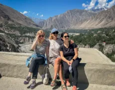 Visitors sitting in the stone courtyard of Baltit Fort overlooking the terraced valley below