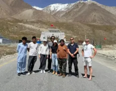 Travelers and local guides celebrating reaching the high-altitude Khunjerab Pass international border