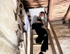 Visitor navigating the ancient carved wooden staircase inside the historic Altit Fort complex