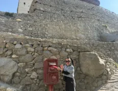 Sightseer dropping a postcard into the vintage British-era red mailbox outside Baltit Fort