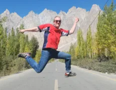 Passu Cones Cathedral Ridge Viewpoint Hiker leaping in the air along the paved Karakoram Highway with Passu Cones in the background