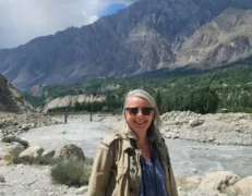 Solo Female Traveler at Indus River Viewpoint Close-up portrait of a solo female traveler with the flowing Indus River, lush green trees, and mountains in the background