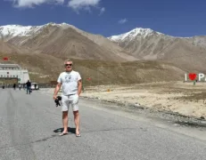 Tourist Sitting Near Khunjerab Pass Border Foreign male tourist sitting and smiling on the road near the Pak-China border gate at Khunjerab Pass